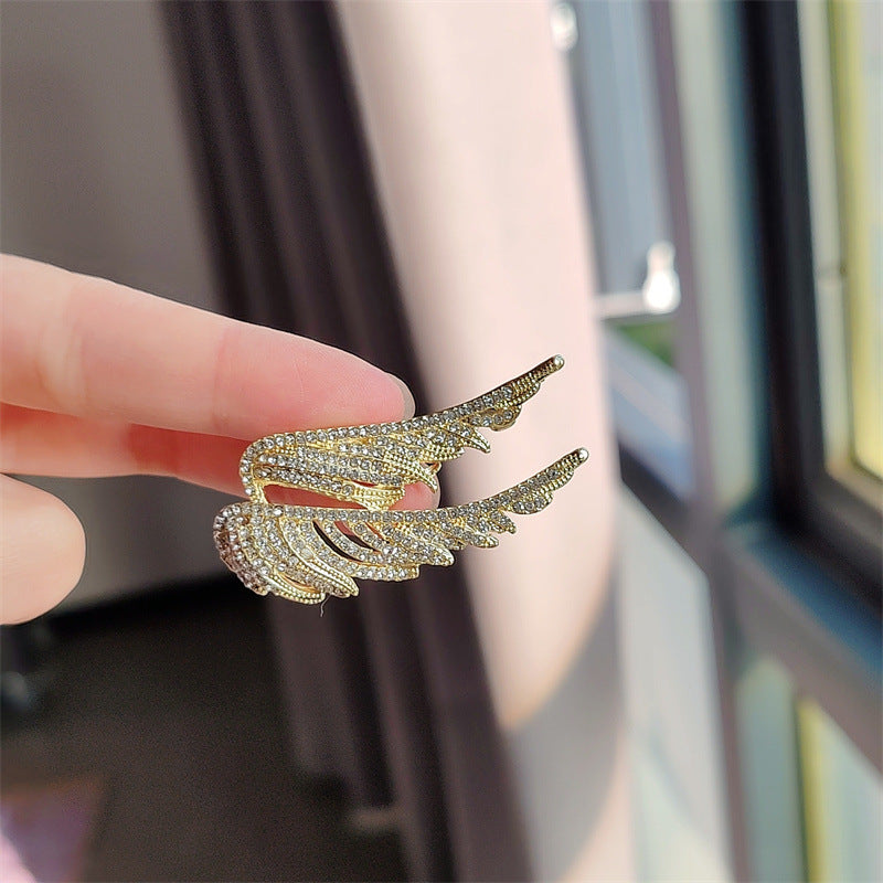 Gold angel wings brooch on white background