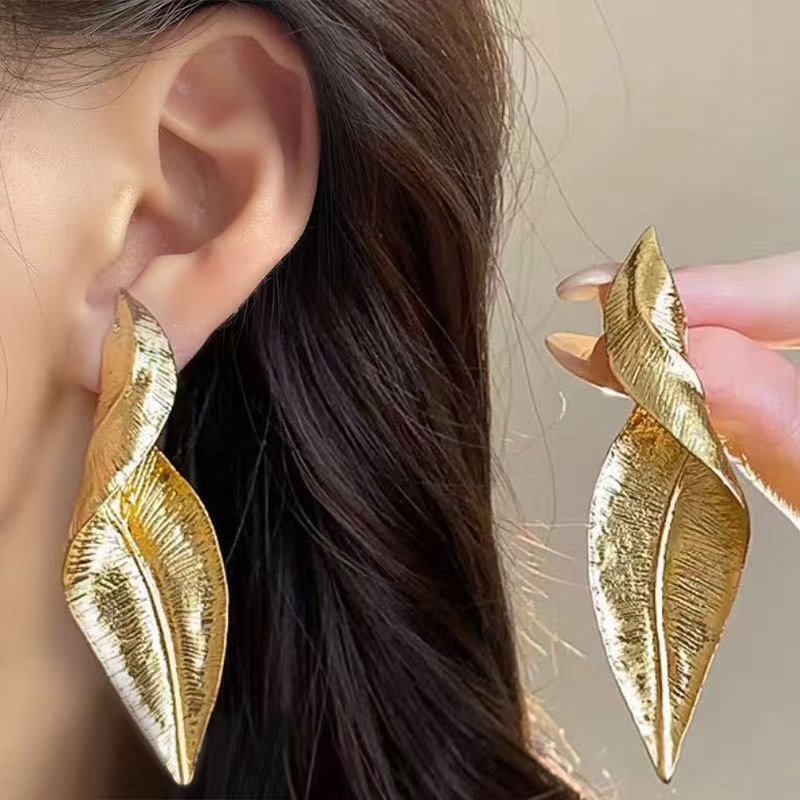Detail of gold leaf earrings against a white background
